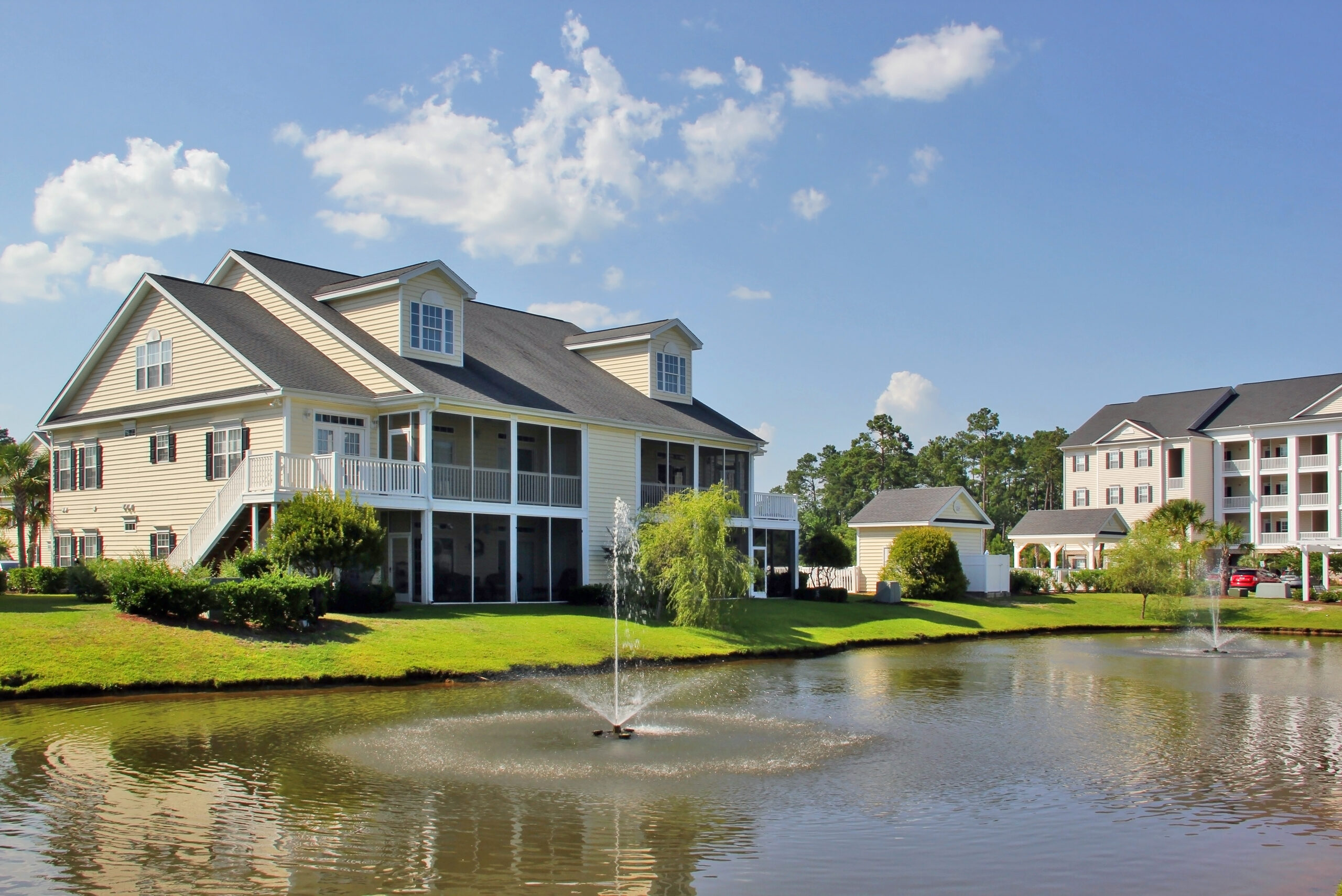 Myrtle Beach suburb morning view with buildings around the pond with sprinkling fountain. South Carolina, USA.