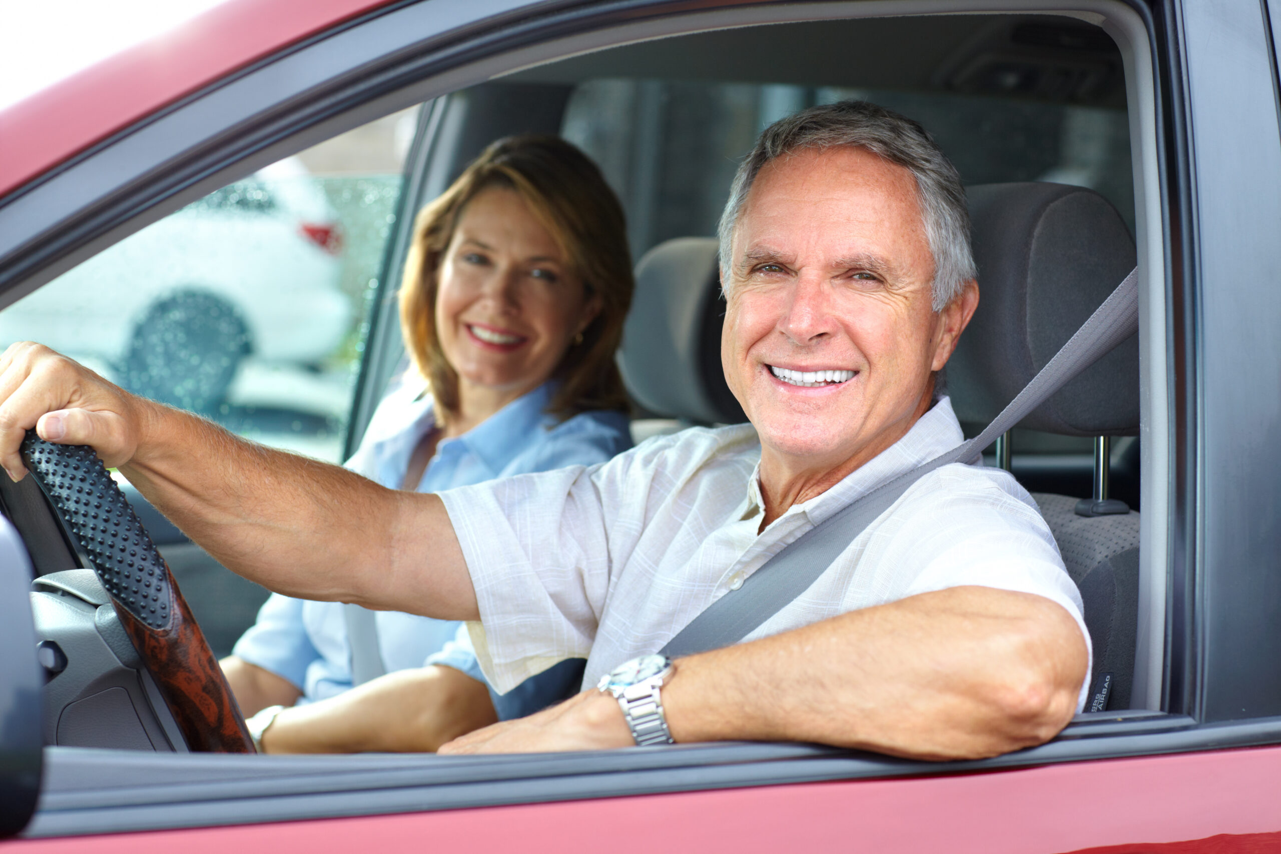 Smiling happy elderly couple in the car